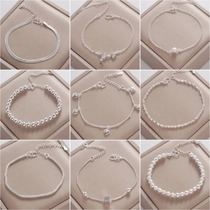 Collection of nine silver chain bracelets featuring heart and star pendants on beige cushion