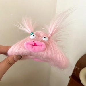Close-up of cute pink plush monster hair claw with big eyes and funny thick lips