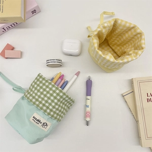 Flat lay of foldable mint green and yellow plaid stationery pouches on a white desk