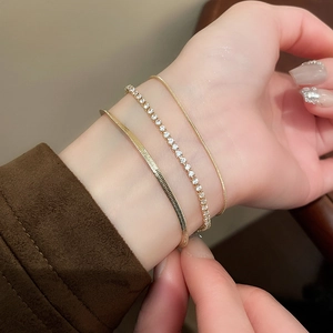 Close-up of three-piece gold snake bone and zircon tennis bracelets stacked on wrist