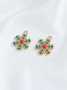 Macro view of gold-plated snowflake charms with festive red and green enamel details