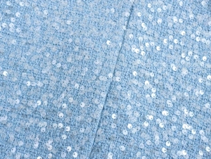 Macro shot of light blue tweed fabric with shimmering sequins for stylish jacket