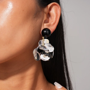 Close-up of model wearing resin marble flower earrings with black sphere stud details