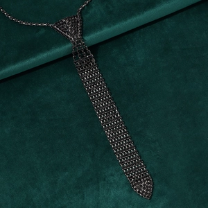 Detailed close-up of a black rhinestone tie necklace on a luxury green velvet background
