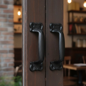 Industrial vintage black cast iron door handle with matte texture on dark wood door