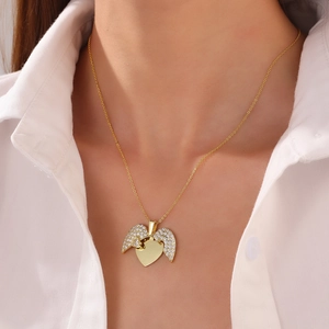 Close-up of a gold heart pendant with wings and pavé crystals on a delicate necklace