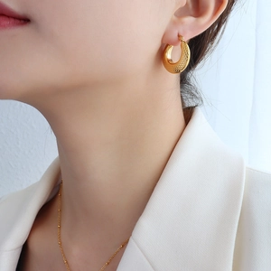 Boucles d'oreilles créoles texturées en plaqué or 18 carats portées par un mannequin