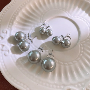 Set of four pairs of vintage grey faux pearl stud earrings on a white ceramic plate