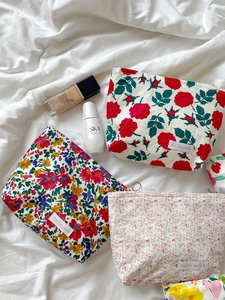 Close-up of three floral fabric cosmetic bags featuring colorful rose and wildflower patterns