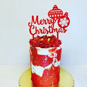 Red acrylic Merry Christmas cake topper with festive baubles on a decorated cake