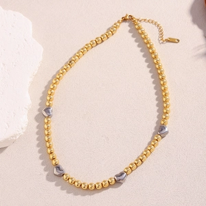 Dettaglio della collana con perle dorate e cuori argentati con chiusura a moschettone