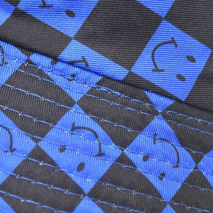 Close-up of blue and black checkerboard fabric with smiley face pattern and stitching