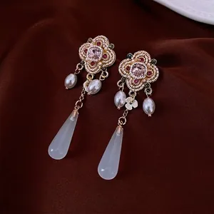 Vintage floral drop earrings with pink resin stone and pearls on red velvet