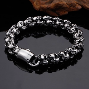 Detailed view of punk style silver skull links bracelet on a dark reflective surface