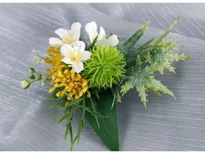 Detail of faux wedding boutonniere with white flowers, yellow clusters and green foliage