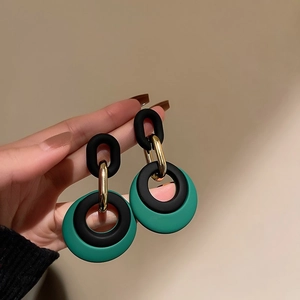 Detail shot of vintage heart pearl earrings with green and black geometric matte rings