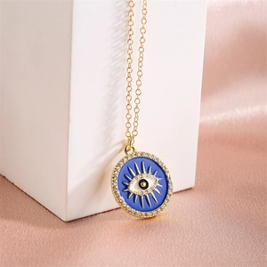 Macro shot of gold-plated evil eye pendant with blue enamel and sparkling zircon stones