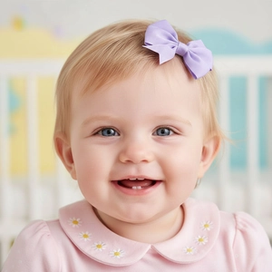 Detail of a purple grosgrain ribbon bow hair clip worn by a smiling infant girl