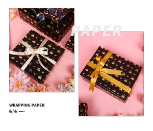 Detail of black gift wrapping paper featuring gold embossed crowns and hearts patterns