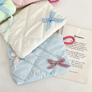 Close-up of quilted satin makeup bags in pastel colors with stylish ribbon bow details