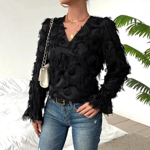 Detail of elegant black deep V-neck shirt featuring textured fringe and flared sleeves