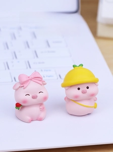 Mini pink resin pigs desk ornaments with rose and hat on white laptop keyboard