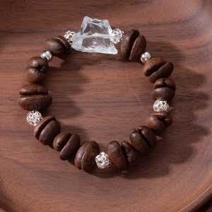 Detailed close-up of a coffee bean bracelet with metal beads on a vintage wooden tray