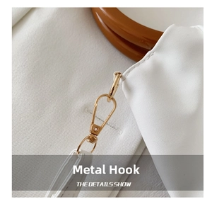 Detailed close-up of premium gold hardware hook and white leather strap of the cloud bag