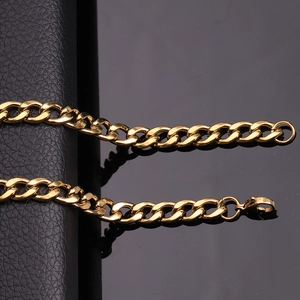Macro shot of gold stainless steel Cuban chain link on a textured black leather background