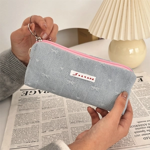 Close-up of denim fabric pencil case with pink zipper and embroidered details