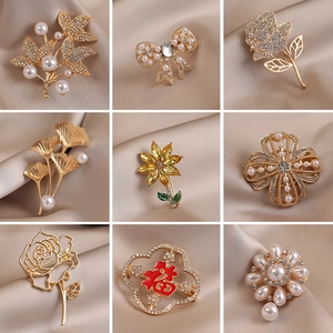 Golden alloy brooch set with pearls and rhinestones on elegant silk background