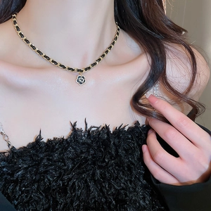 Detail of camellia pendant necklace with gold plated chain and woven faux leather