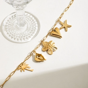 Detailed macro view of 18K gold stainless steel bracelet with diverse beach charms