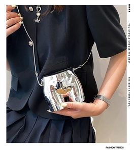 Close-up of a silver chrome mini crossbody bag with a creative artistic female torso design
