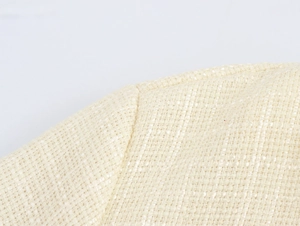 Gros plan sur la texture du tissu en tweed beige et les détails tissés de l'épaule