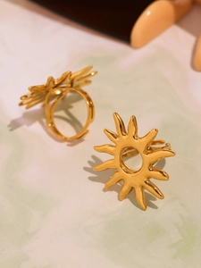 Close-up of 18k gold plated hollow sun rings on a green marble surface