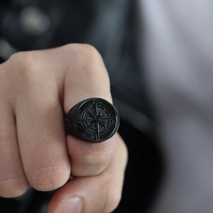 Close-up of retro black matte stainless steel compass ring on a male model hand
