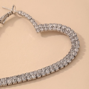 Macro shot showing detail of white rhinestones set in heart-shaped silver hoop earrings
