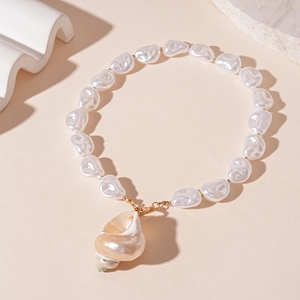 Detailed shot of ocean style shell pendant with white faux baroque pearls on gold necklace