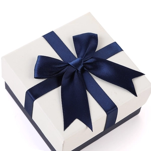 Square jewelry gift box with white textured lid and navy blue ribbon bow accent