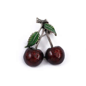 Elegant red cherry brooch pin with green leaves on white background for women