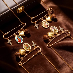 Close-up of golden paperclip necklaces with religious cross and Mary heart pendants