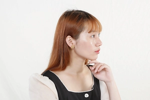 Detailed view of elegant gold woven flower earrings on model with polished metal finish