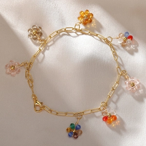 Dettaglio di ciondoli a fiore in cristallo su bracciale dorato su fondo in raso