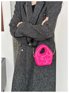 Close-up of bright pink vintage telephone-shaped crossbody bag with metal chain strap