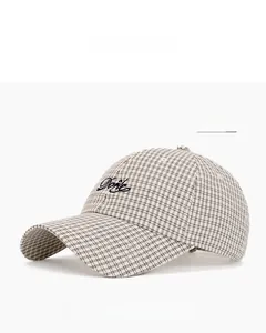 Close-up of beige plaid baseball cap with blue Done script embroidery and breathable fabric