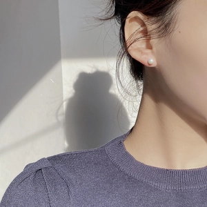 Close-up of 925 sterling silver pearl stud earring worn on a female ear model