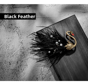 Detail of vintage swan brooch with black feathers and pearls on dark wood base