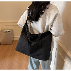 Rear view of a model wearing a black large canvas tote bag showing draped shape and capacity