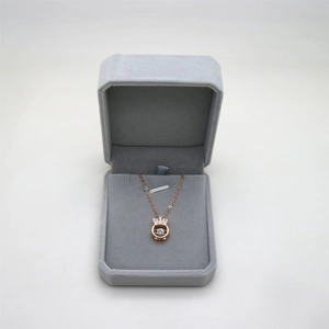 Octagonal grey velvet jewelry box with rose gold crown pendant and sparkling necklace